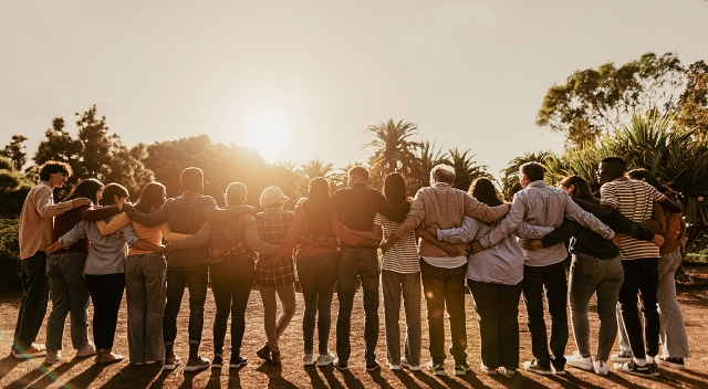 Gruppe von Menschen hält sich im Arm bei Sonnenuntergang juwelier-leicht-engagement